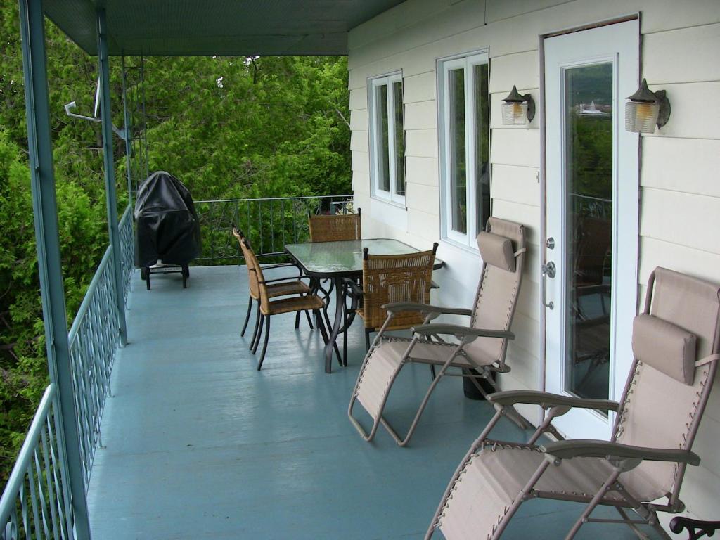 une terrasse couverte avec une table et des chaises. dans l'établissement La Source Enchantée, à Baie-Saint-Paul