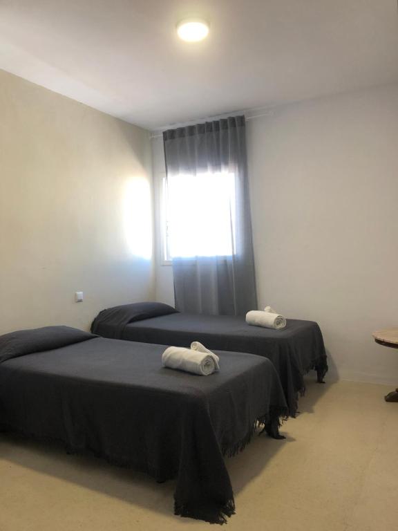 2 camas en una habitación con ventana en Hostal Santa Calma, en Marbella