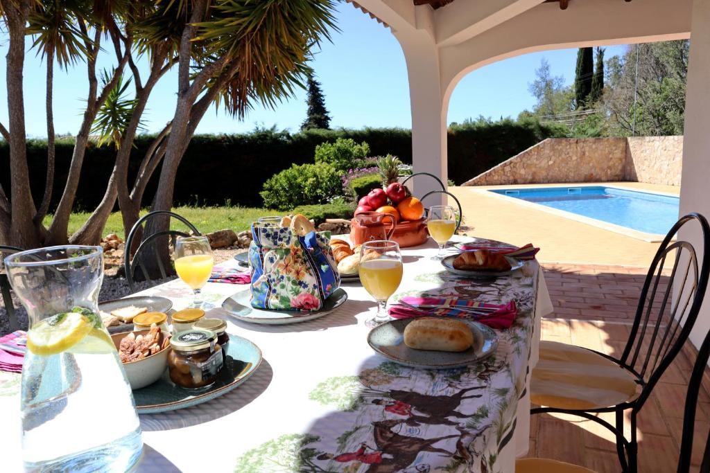 una mesa con comida y bebidas con una piscina en Villa Laranjal, en Mexilhoeira Grande