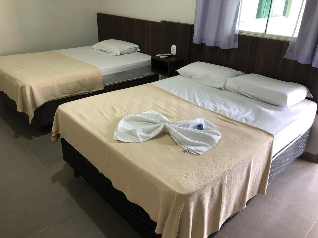 two beds in a hotel room with a robe on them at Hotel Hawaii in Colíder