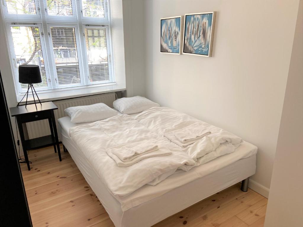Cama blanca en habitación con 2 ventanas en Cozy apartment in elegant Østerbro, en Copenhague