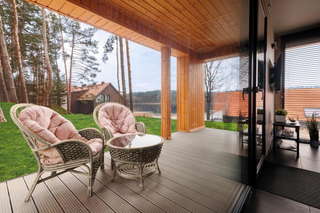 - une terrasse couverte avec 2 chaises et une table dans l'établissement Dom nad Jeziorem - Perfect Stay, à Tomaszkowo