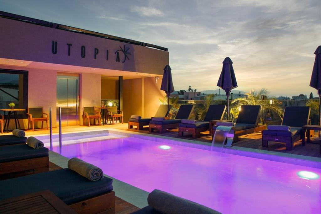 una gran piscina con sillas y un edificio en Utopia Luxury Suites, en Platanes