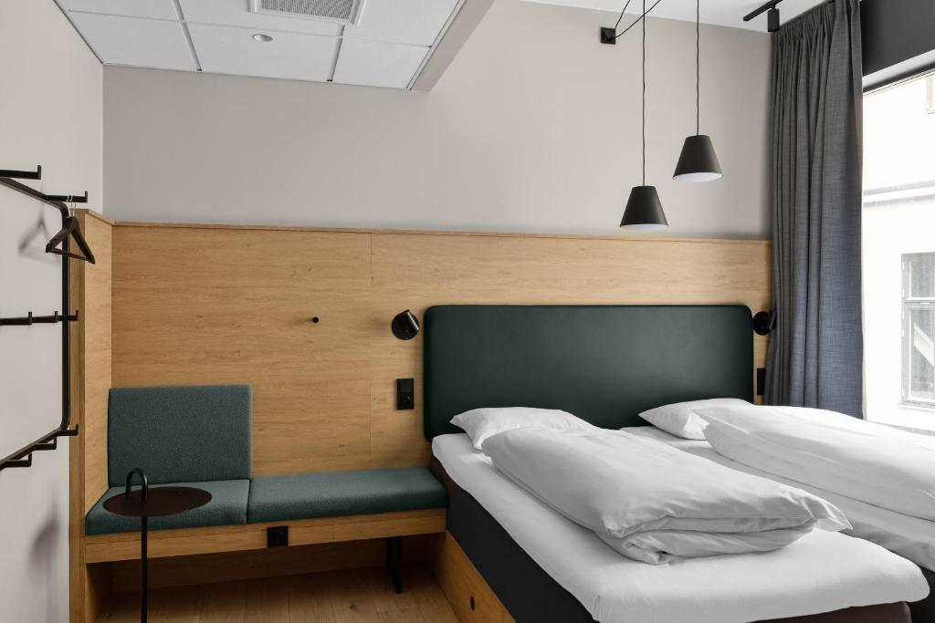 a bedroom with two beds and a bench in it at Comfort Hotel Xpress Youngstorget in Oslo