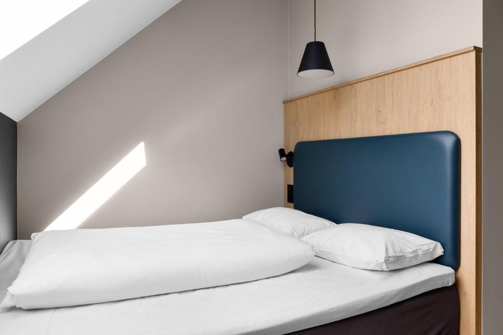 a bed with white sheets and a blue headboard at Comfort Hotel Xpress Youngstorget in Oslo