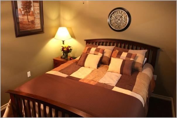 ein Schlafzimmer mit einem Bett und einer Uhr an der Wand in der Unterkunft Eagle's Den Three Rivers Texas a Travelodge by Wyndham in Three Rivers