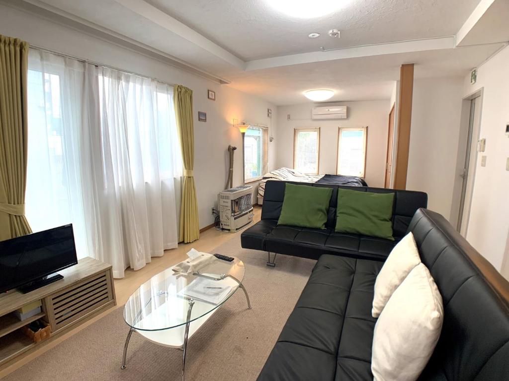 a living room with a black couch and a tv at Nagayama Home in Asahikawa
