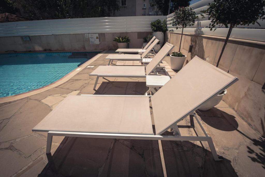 a row of picnic tables next to a swimming pool at Chrielka Hotel in Limassol