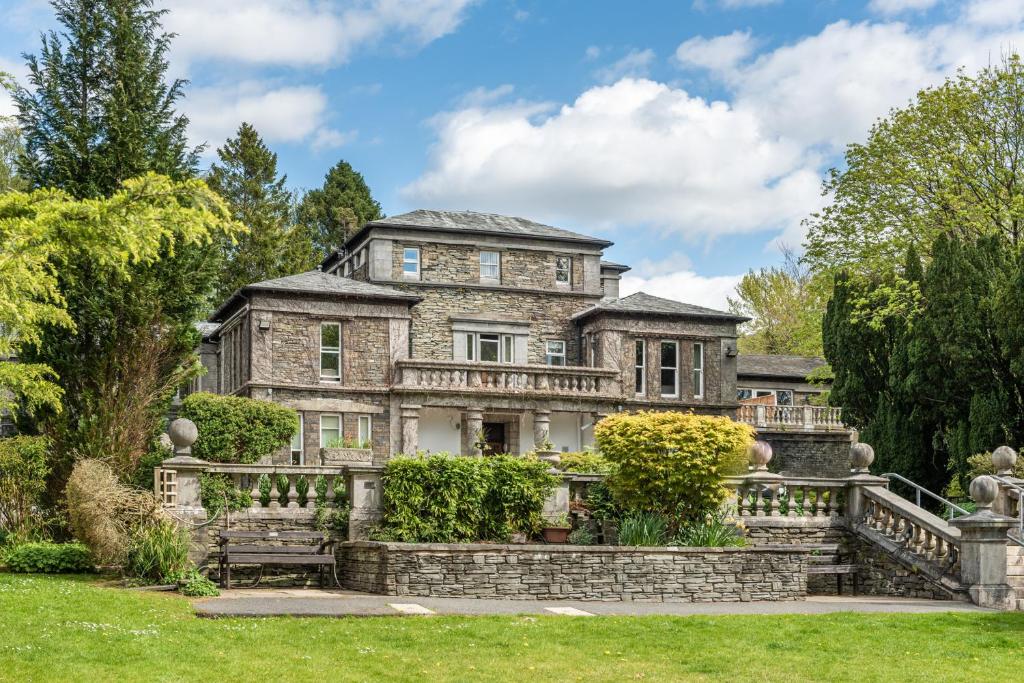 een oud stenen huis met een stenen trap in een tuin bij Windermere Manor Hotel in Windermere