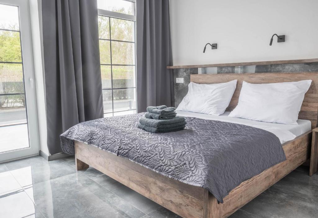 a bedroom with a bed with a wooden headboard and windows at Veltlin Bed & Wine in Valtice