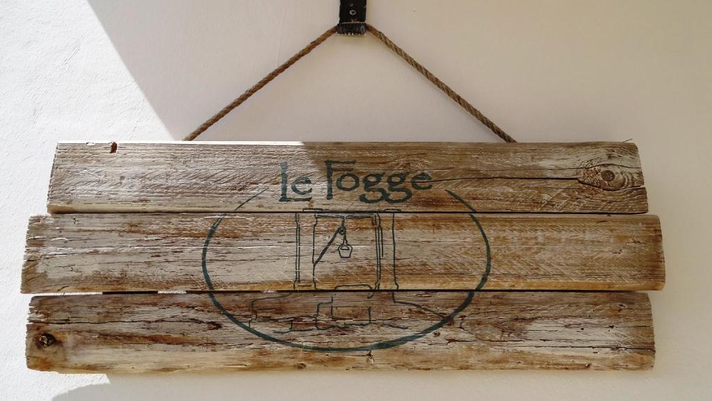 a wooden sign hanging on a wall at Le Fogge in Fasano