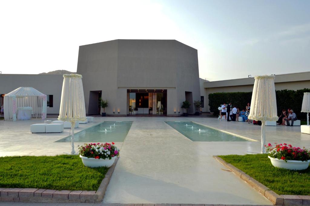 un gran edificio con piscina y 2 sombrillas en Desusino Residence & Hotel, en Butera