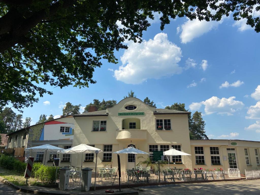 a building with tables and umbrellas in front of it at Waldwerk Wurlgrund Lychen in Lychen