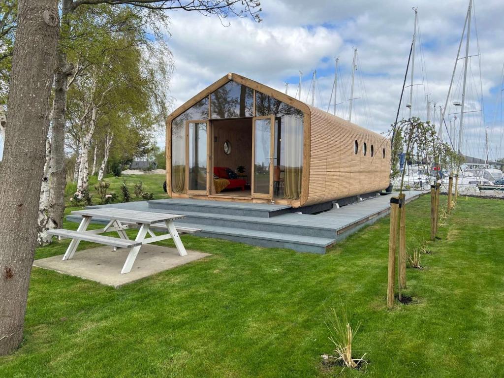 a small wooden house with a picnic table in a field at Wikkelhuis 31- Pet Friendly in Stavoren