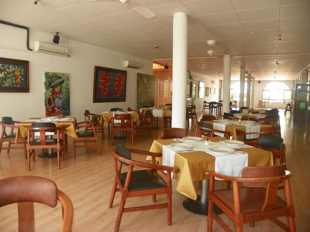 a dining room with tables and chairs with yellow table cloth at Hotel Royal Plaza in Florencia