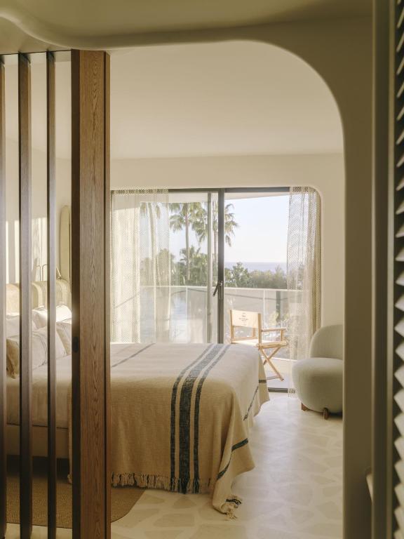 a bedroom with a bed and a large window at Hôtel & Spa Belle Plage in Cannes