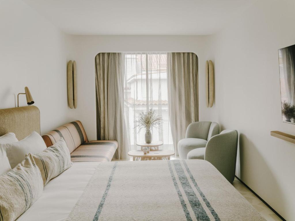 a bedroom with a bed and a couch and a window at Hôtel & Spa Belle Plage in Cannes