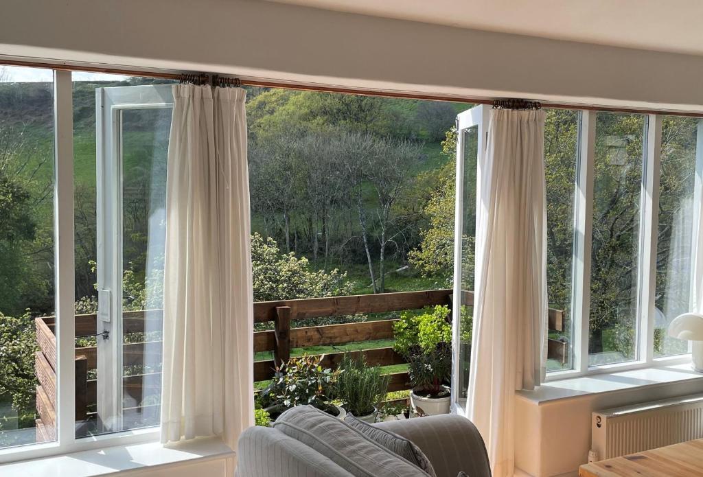 a living room with a large window with white curtains at Little Winters Cottage in Lyme Regis