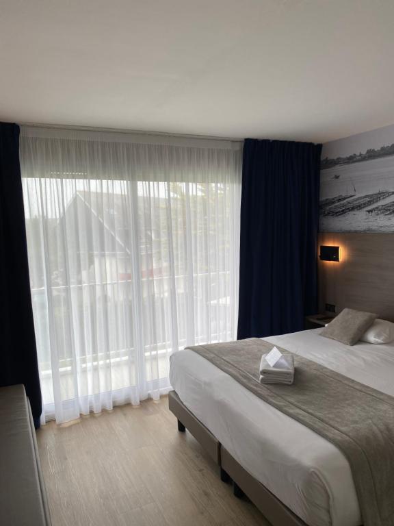 a bedroom with a large bed and a large window at Hotel Europa in Quiberon