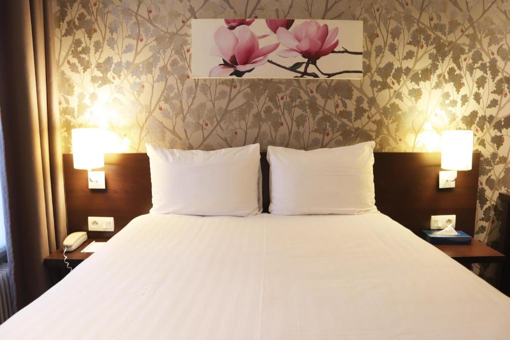 パリにあるティモテル オデッサ モンパルナスのベッドルーム(白い大型ベッド、ランプ2つ付)