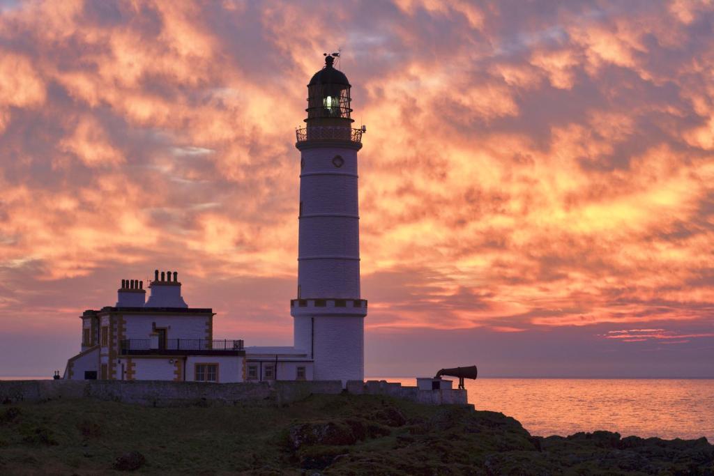 a lighthouse sitting on top of a hill next to the ocean at Corsewall Lighthouse Hotel in Kirkcolm