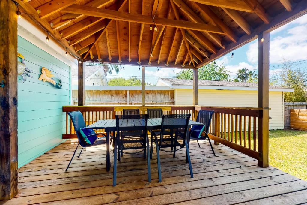 une terrasse en bois avec une table et des chaises. dans l'établissement Playa Perch, à Galveston