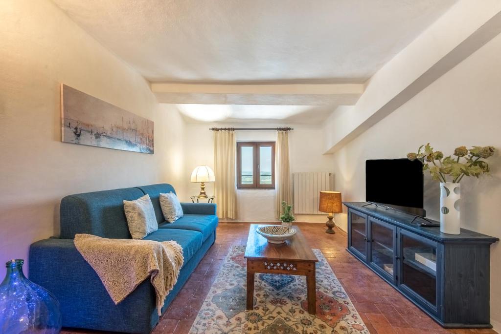 un salon avec un canapé bleu et une télévision dans l'établissement Appartamento Panoramico, à Radicondoli
