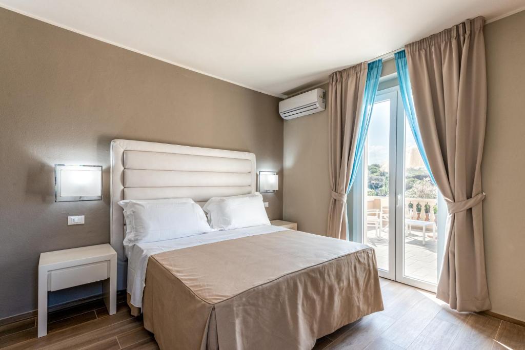 a bedroom with a bed and a large window at Hotel Villa Bolgheri in Marina di Castagneto Carducci
