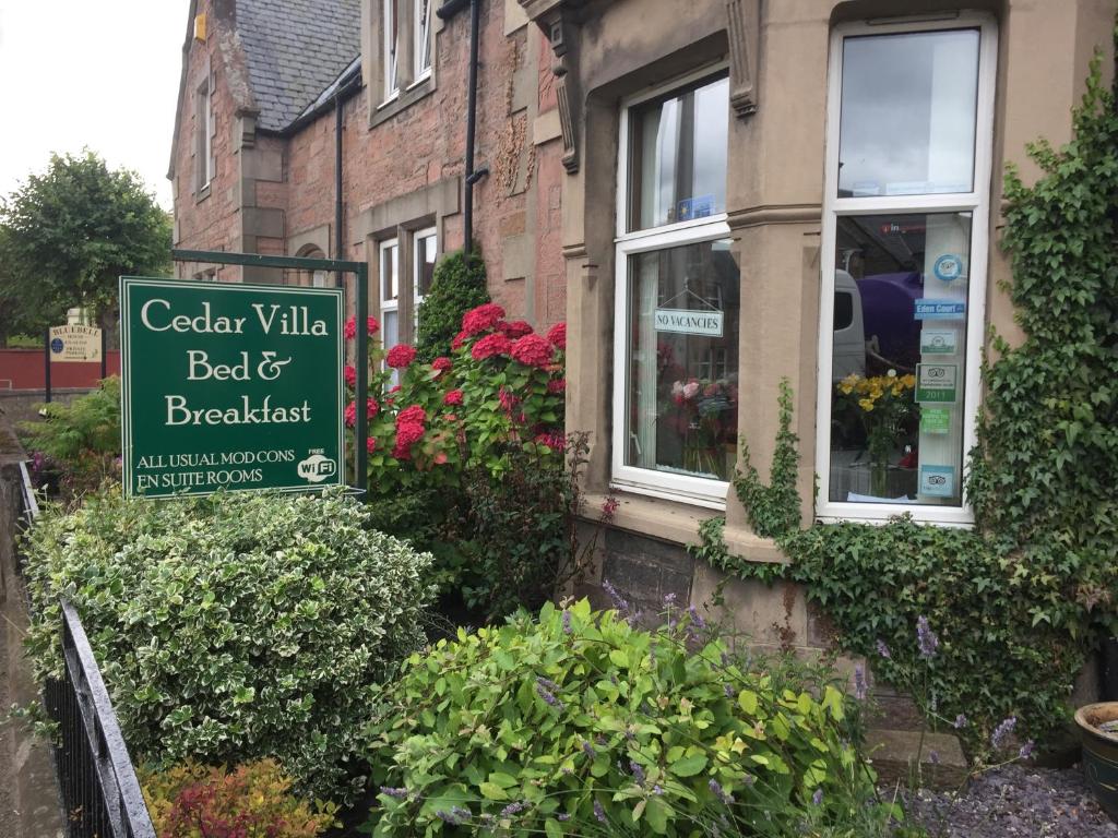 ein Schild für ein Bed & Breakfast vor einem Gebäude in der Unterkunft Cedar Villa Guest House in Inverness