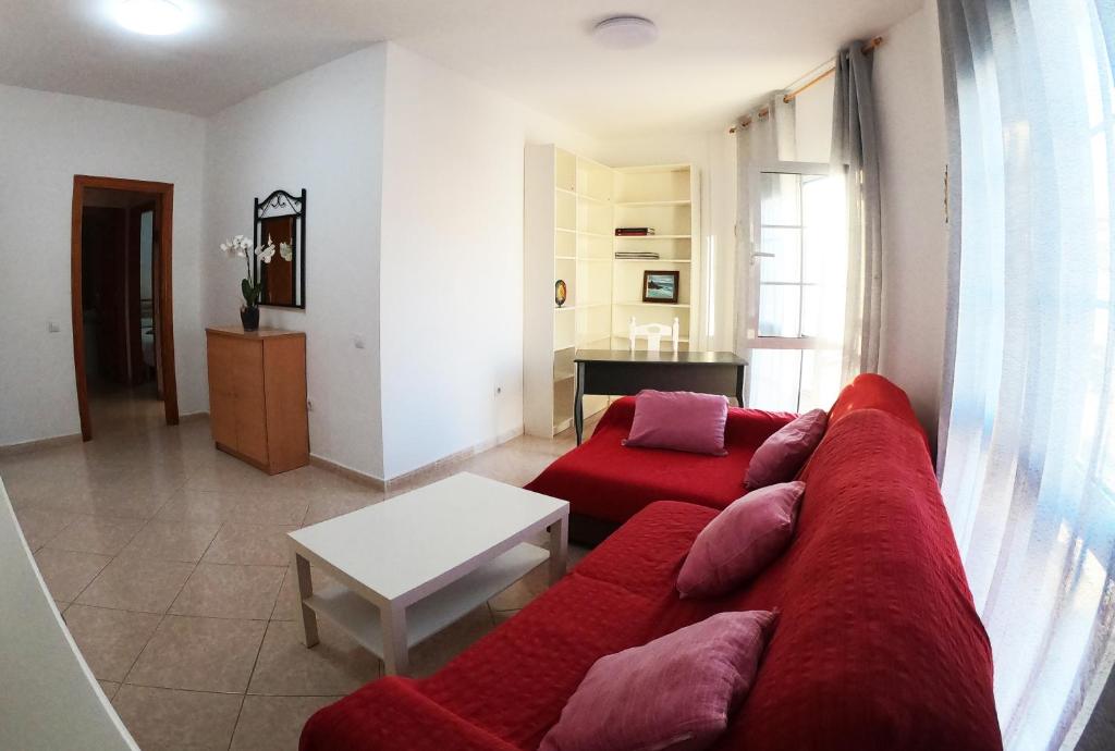 a living room with a red couch and a table at Apartamento junto el mar in Gran Tarajal