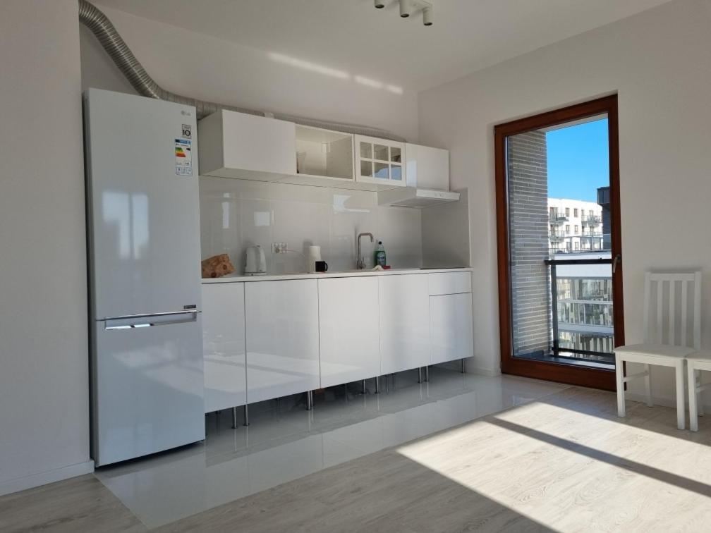 a white kitchen with a refrigerator and a window at Apartament Chrobrego in Gdańsk