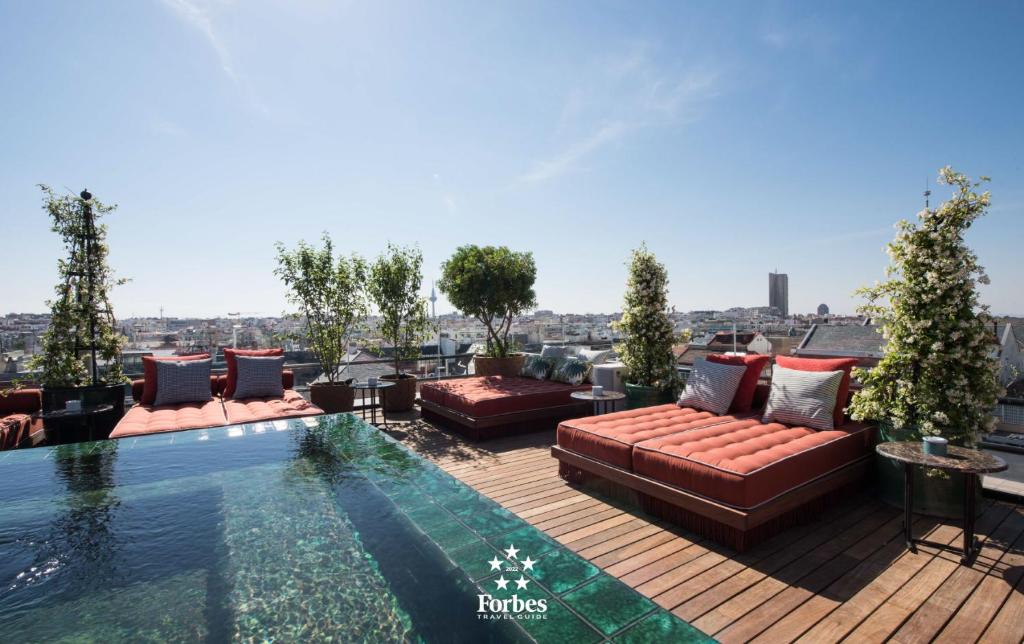 a rooftop patio with a couch and a swimming pool at BLESS Hotel Madrid - The Leading Hotels of the World in Madrid