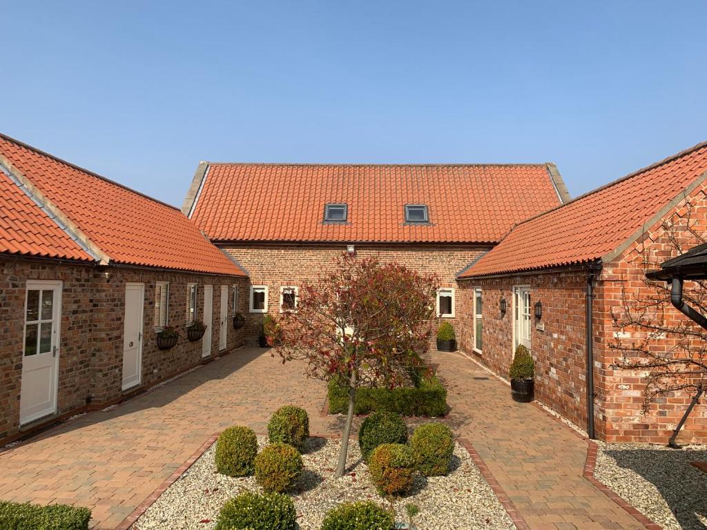 eine Reihe von Backsteingebäuden mit orangefarbenen Dächern in der Unterkunft Meals Farm - Courtyard Room in North Somercotes