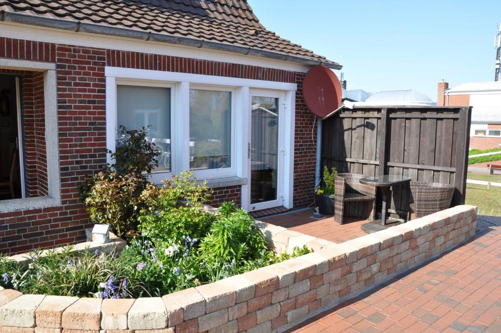 um pátio de tijolos com uma mesa e uma cerca em Ferienhaus Nordstrand Whg 3 em Baltrum