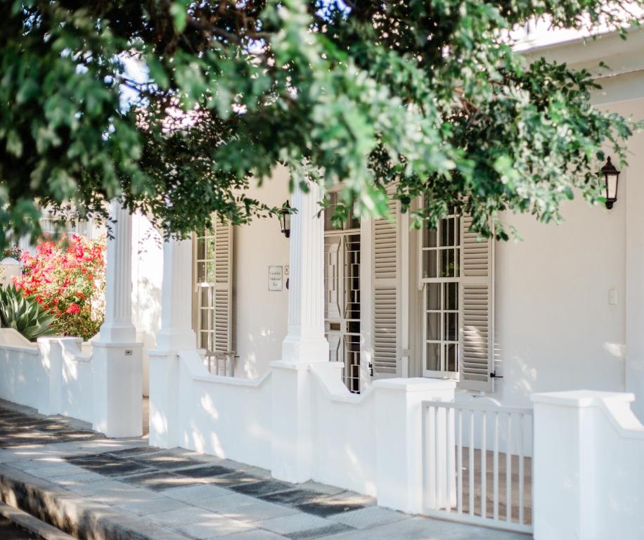 a white house with shuttered windows and trees at The River Bend Cottages in Graaff-Reinet