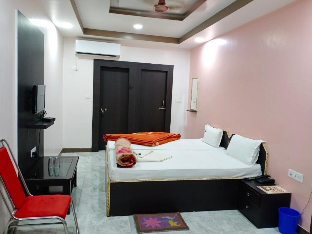 a bedroom with a bed and a red chair at Hotel Sunaina International in Gaya