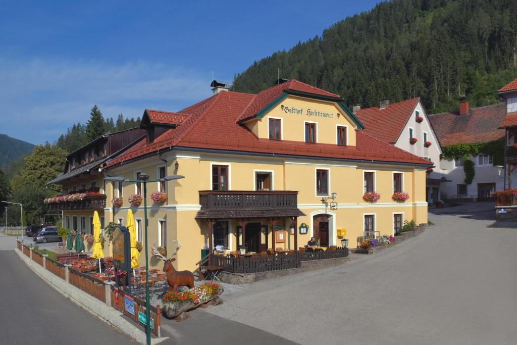 um grande edifício amarelo com um telhado vermelho numa rua em Gasthof Hirschenwirt em Schöder