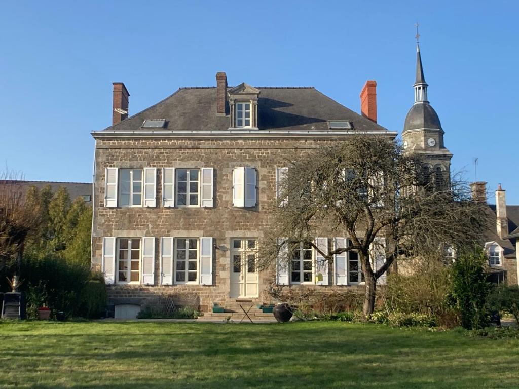 um grande edifício de tijolos com uma torre de relógio sobre ele em Maison d'hôtes La Doucelle em Lignieres-Orgeres