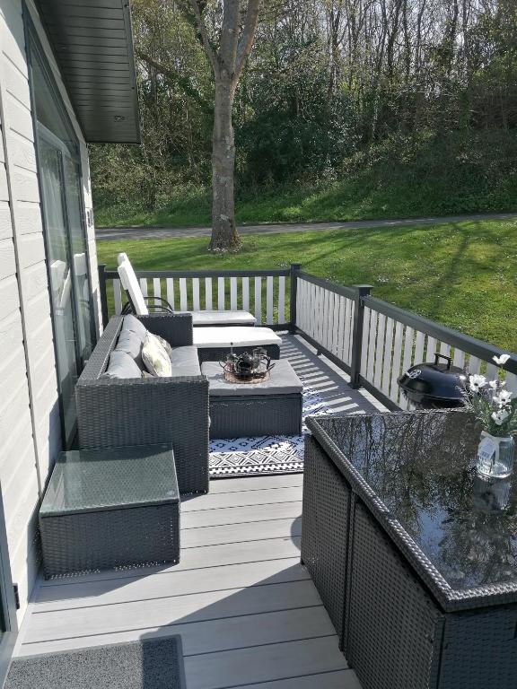 a patio with a couch and a table on a porch at STUNNING, PEACEFUL LODGE on edge of New Forest and 800m from sea ENTERTAINMENT and LEISURE PASSES INCLUDED in Milford on Sea