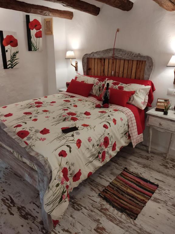 Un dormitorio con una cama con flores rojas. en El Racó de la Civaderia, casa en Montblanc, en Montblanc