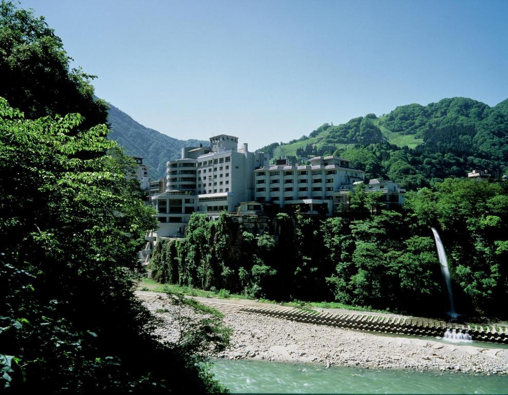 a building on a hill next to a river at Entaijiso in Kurobe