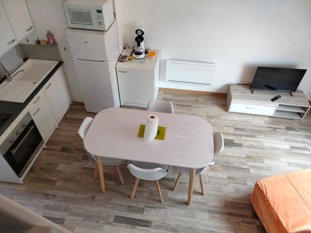 eine kleine Küche mit einem weißen Tisch und Stühlen in der Unterkunft STUDIO-COSY in Bourbourg