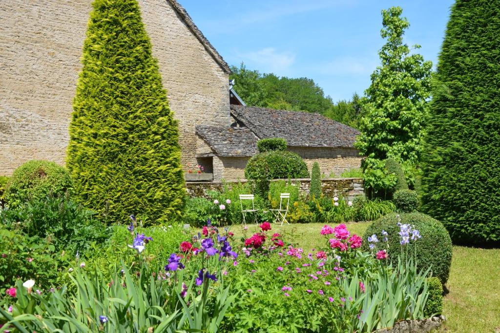 a garden in front of a house with flowers at La ferme aux glycines in Aillevans