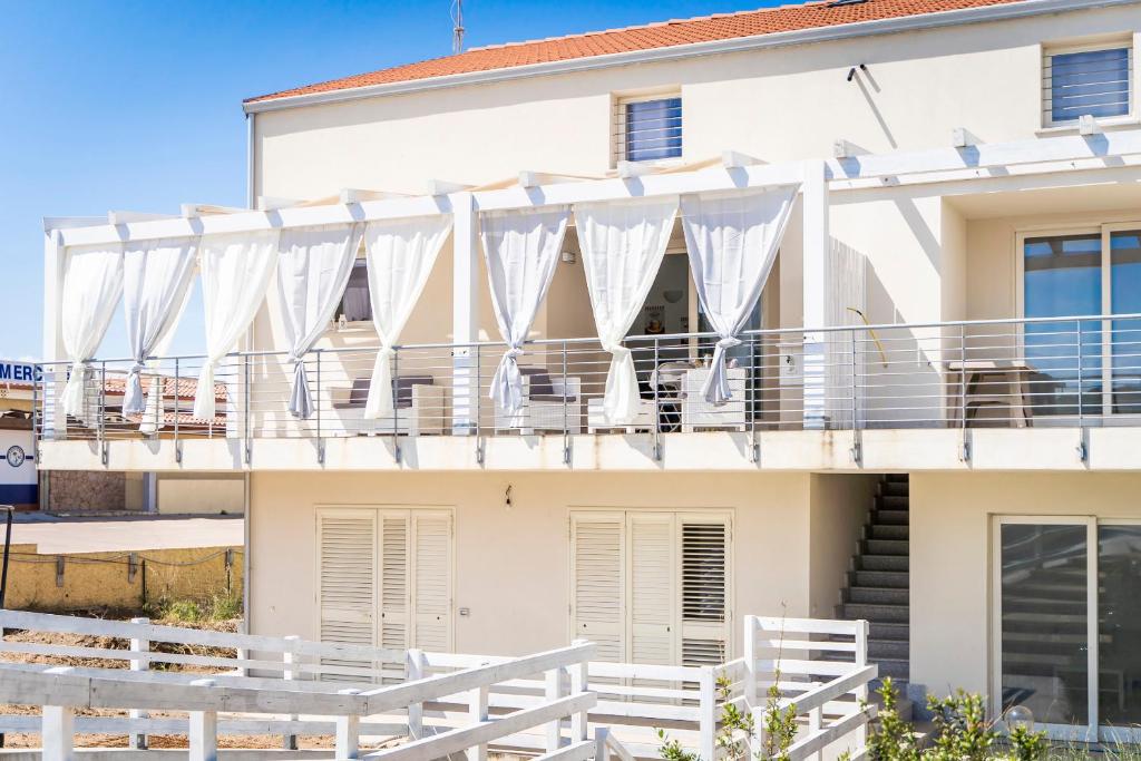 una casa bianca con tende bianche sul balcone di Ulivi 17 a Isola Rossa