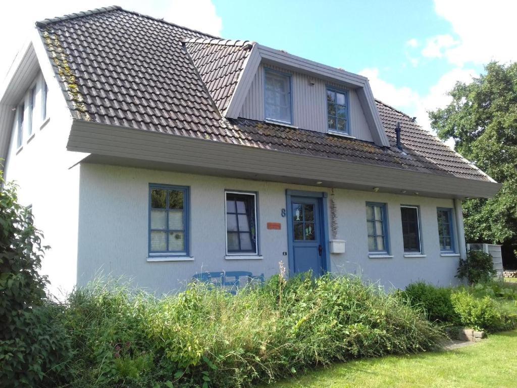 una piccola casa bianca con una porta blu di Ferienwohnung Born am Darßwald EG a Born