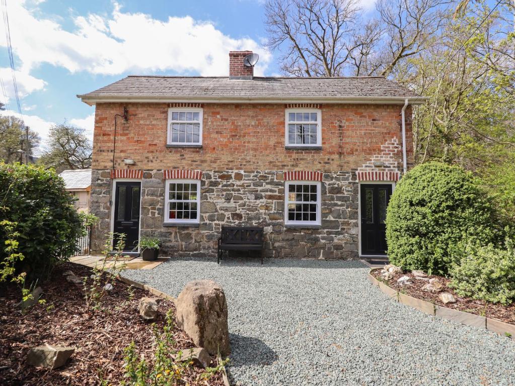 an old brick house with a gravel driveway at Tan Y Capel in Llanbrynmair
