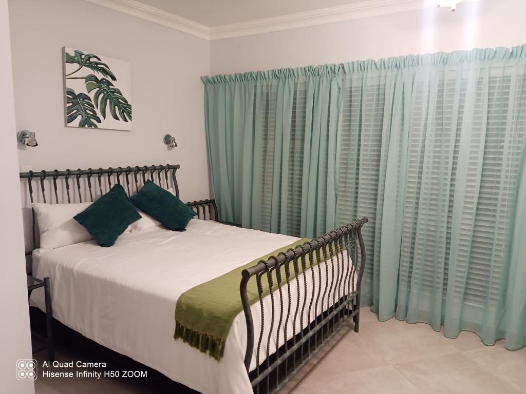 a bedroom with a bed and green curtains at 4 on Verbena in Boksburg