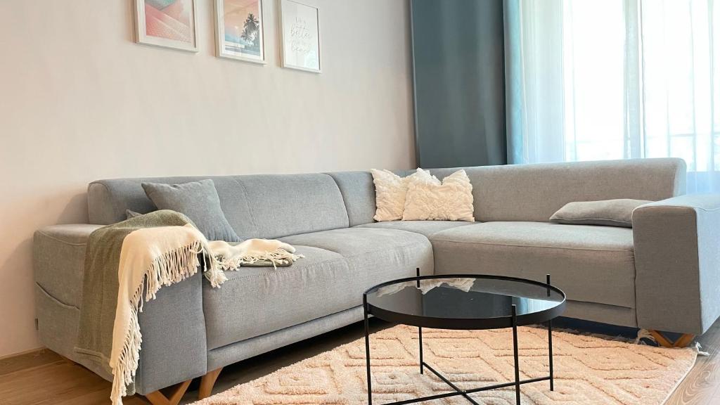 uma sala de estar com um sofá cinzento e uma mesa de vidro em Sunny Pobierowo Euronia Apartament em Pobierowo