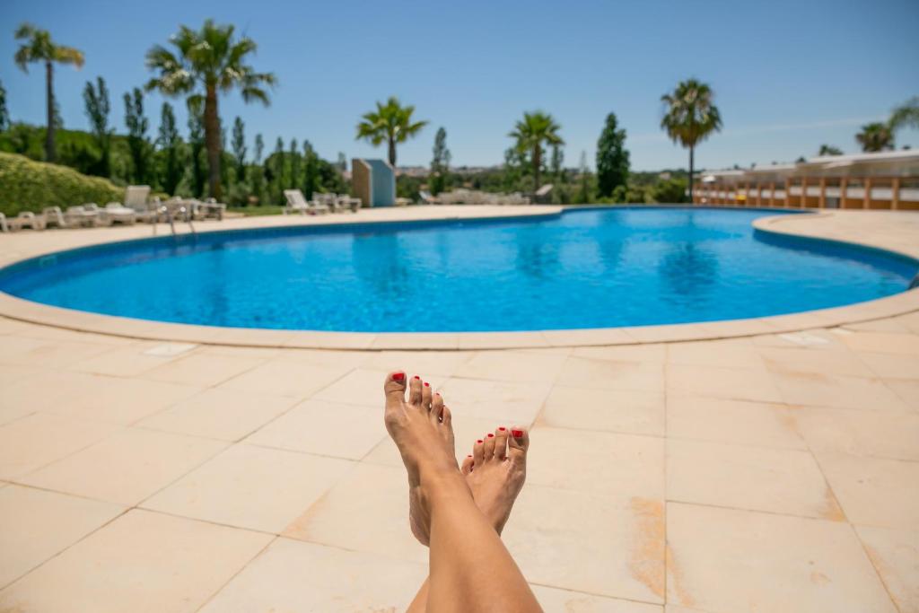 Eine Frau mit den Füßen vor einem Pool in der Unterkunft Sunny villa facing the swimming pool in Fontainhas