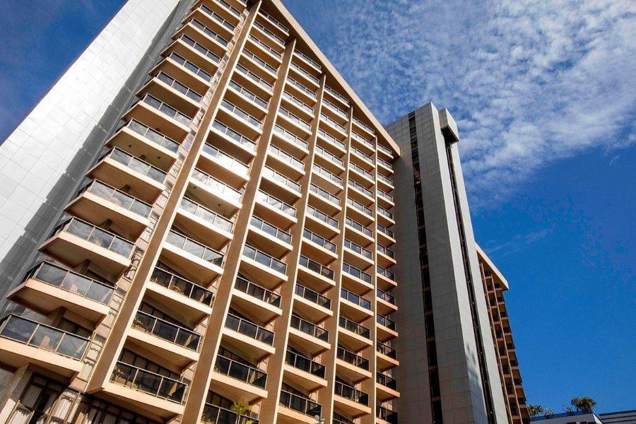 um edifício de apartamentos alto com um céu azul ao fundo em Flat Particular Hotel Kubitschek em Brasília